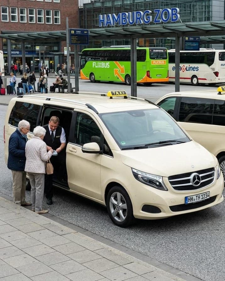 Zwei helle Großraumtaxis am Busbahnhof ZOB Hamburg, an der offenen Schiebetür spricht ein Fahrer mit zwei älteren Frauen, dahinter Fernbusse